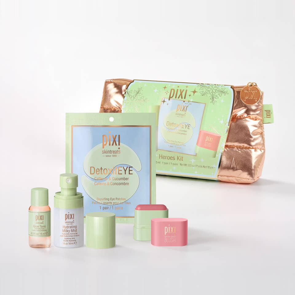 Pixi+ Skintreats Heroes Kit skincare set on a clean white background, featuring a metallic rose gold zippered pouch, a light green sachet, a small pink jar, a light green bottle, and other matching skincare containers. view 1