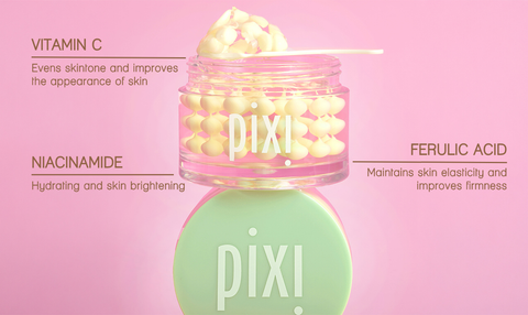 Pixi Vitamin CremeSerum jar with a mint green cap and clear jar showing yellow serum, set against a solid pink background with text detailing the ingredients.
