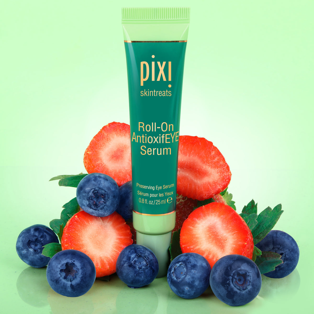 PIXI Roll-On AntioxiFEYE Serum surrounded by strawberries and blueberries on a green background