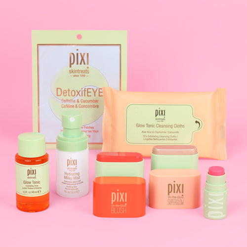 Pixi Skintreats skincare and makeup set arranged on a pink background, including DetoxifEYE pouch, cleansing wipes, toner, moisturizer, blush, superglow and a small +Hydra Liptreat product. view 1