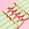 Set of green LipBlush with colorful tips on a pink background