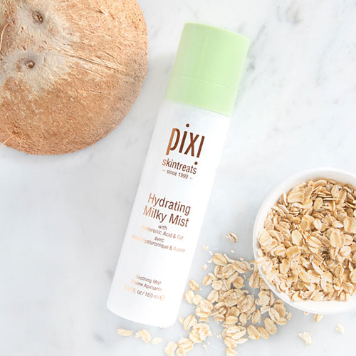 Pixi Hydrating Milky Mist bottle with a coconut and oats on a marble surface