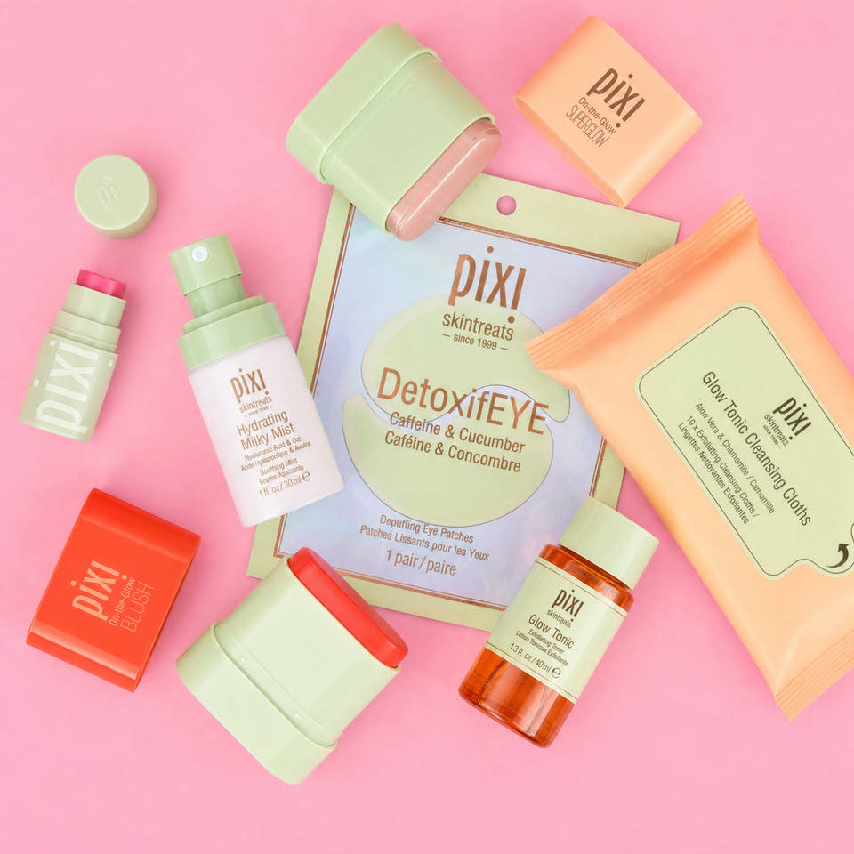 A flat-lay arrangement of Pixi Petites products on a solid pink background, including DetoxiEYE, On-the-Glow Blush and SuperGlow Petites and others. view 2