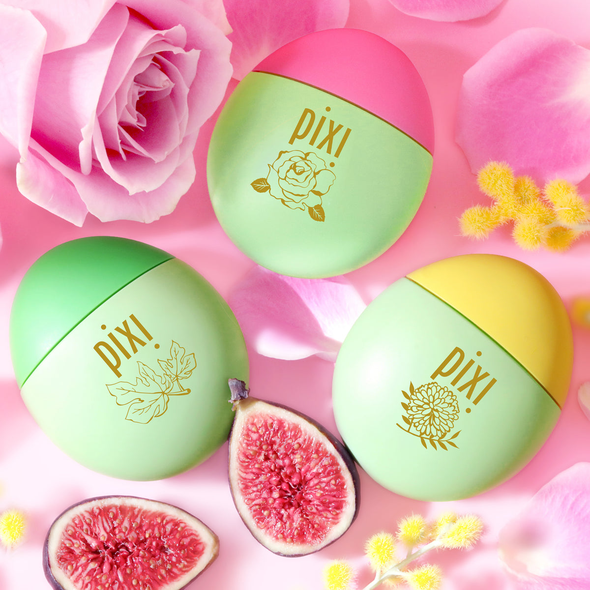 HandHero trio featuring PixiRose, PixiMimosa and PixiFig shown on a pink background with roses, mimosa blooms and figs.  The containers have gold foil illustrations and the Pixi brand name.