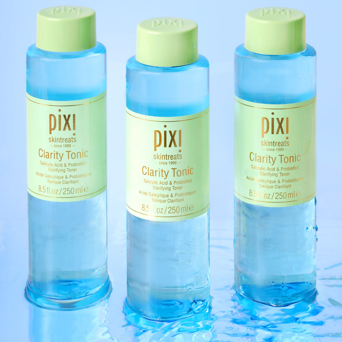 Three bottles of Pixi Clarity Tonic on a light blue background