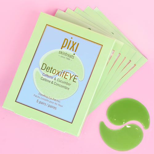 A stack of Pixi Skintreats DetoxiEYE eye gel patches in a light green box, displayed on a pink background with two green gel patches placed in front. view 1