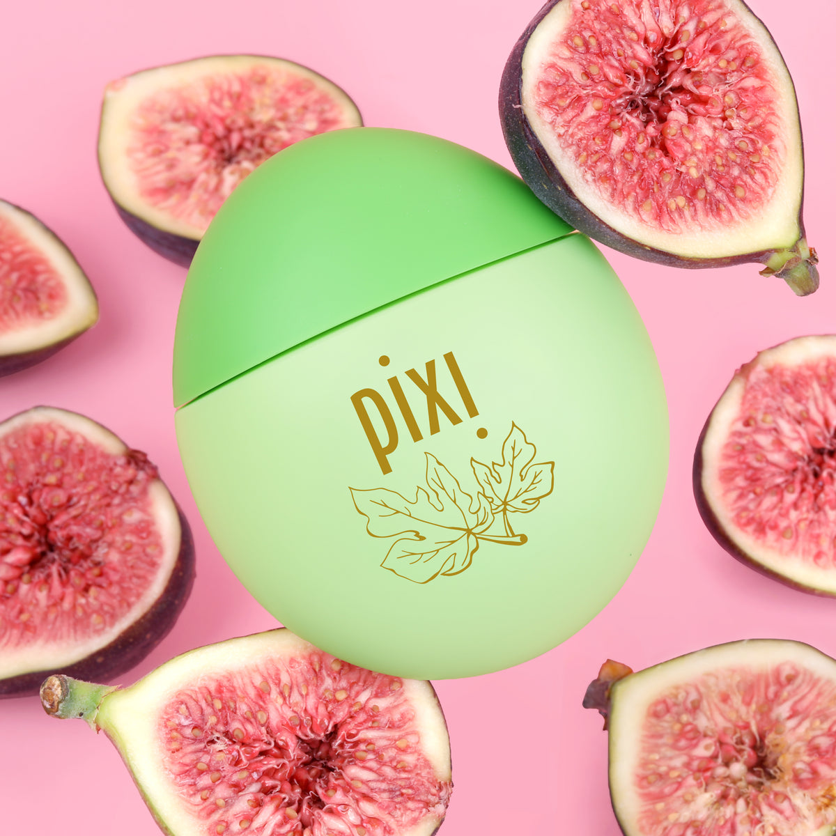 Pixi HandHero PixiFig hand lotion container in a light green egg shape with gold foil branding, surrounded by fresh sliced figs on a solid pink background.