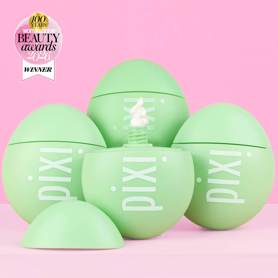Five light green Pixi cosmetic egg-shaped containers arranged on a pink background, with one open container in the center showing white cream and a small award badge in the top-left corner. View 2 view 1