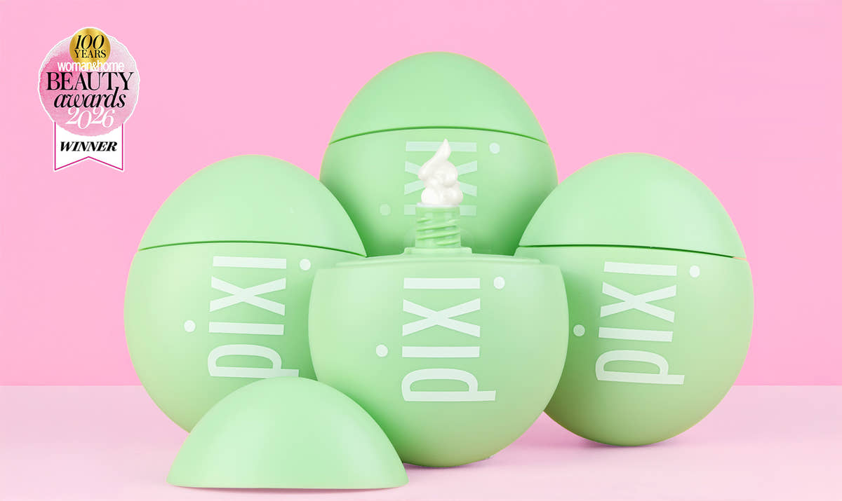 Five light green Pixi cosmetic egg-shaped containers arranged on a pink background, with one open egg showing a white cream product and a Pixi Beauty Awards Winner badge in the top left corner. View 1